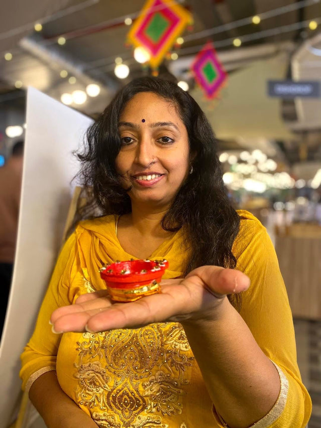A colleague holding a freshly painted red and gold candle holder on an open palm
