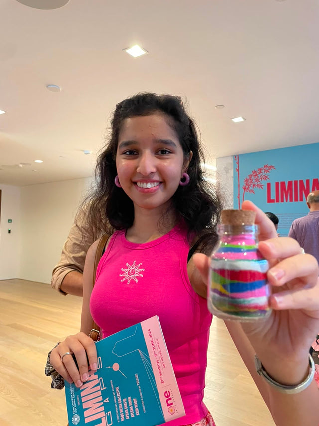 A colleague holding up a jar layered with colored sand, her kit box still in her other hand